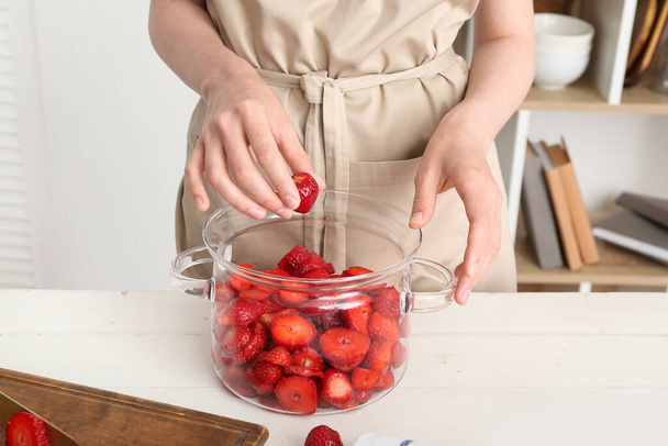 Mujer preparando mermelada de fresa dulce en la mesa en la cocina, primer plano - Foto, imagen
