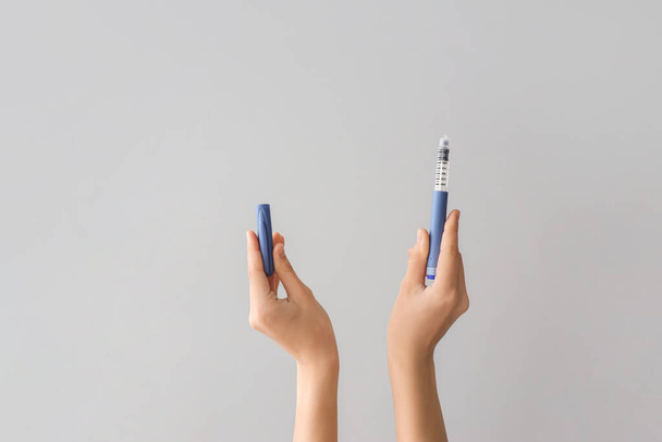 Mani femminili con siringa di insulina su sfondo grigio - Foto, immagini