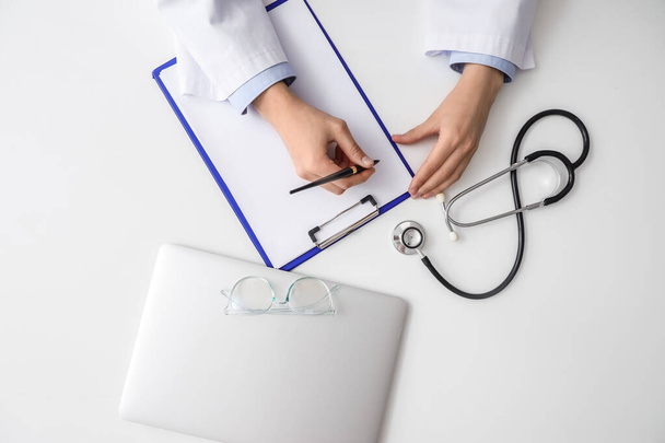 Doctor working with clipboard, stethoscope and modern laptop on white table - Foto, Imagen
