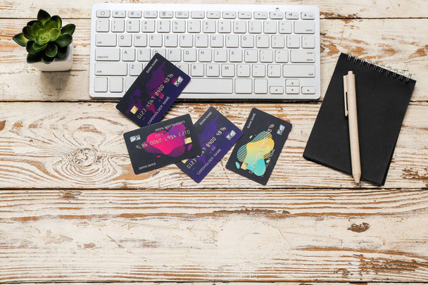 Πληκτρολόγιο με πιστωτικές κάρτες και σημειωματάριο σε ανοιχτό ξύλινο φόντο - Φωτογραφία, εικόνα
