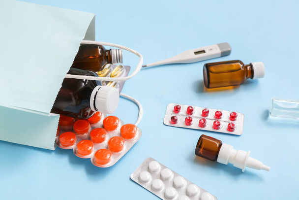 Boodschappentas met verschillende geneesmiddelen op blauwe achtergrond - Foto, afbeelding