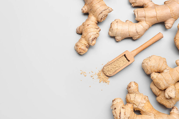 Fresh ginger roots and wooden scoop with dried powder on grey background - Photo, Image