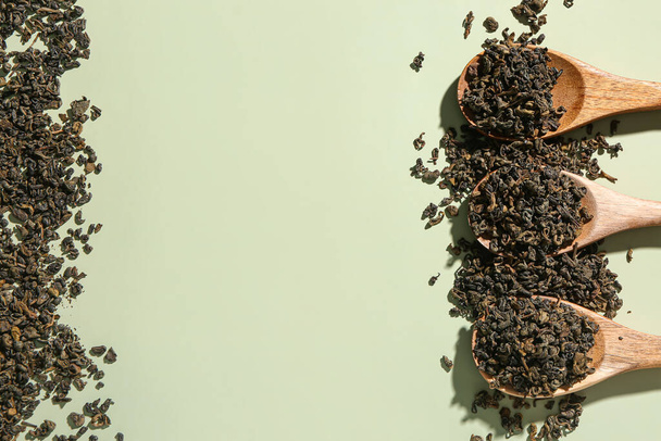 Drewniane łyżki z suchymi liśćmi herbaty na zielonym tle - Zdjęcie, obraz
