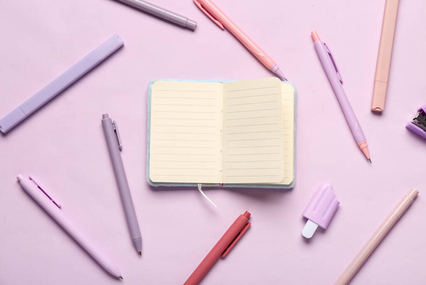 Caderno com diferentes suprimentos de papelaria sobre fundo lilás - Foto, Imagem