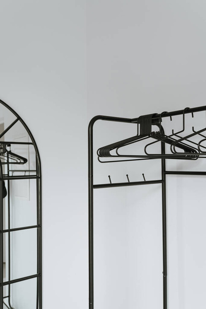 Hangers on floor hanger over white wall. Minimal home wardrobe interior concept - Photo, Image