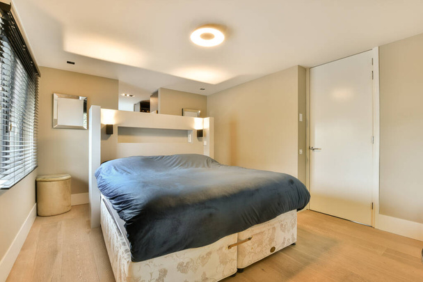 Yatak odası, ahşap döşeme ve beyaz duvarlar, yatak başlığı olarak kullanılan bir yatak odası. - Fotoğraf, Görsel