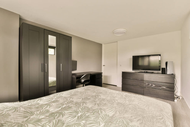 Yatağı, şifoniyeri ve yatağın önündeki duvarda televizyonu olan bir otel odası koyu ahşap. - Fotoğraf, Görsel