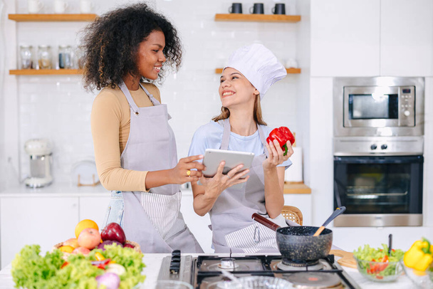 pareja LGBT mujeres amigo vacaciones actividad utilizando tableta tecnología internet ayuda a aprender cocina comida saludable precioso lindo juntos - Foto, imagen