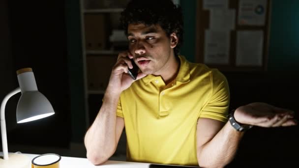 Fiatal latin férfi üzletember vitatkozik okostelefonon dolgozik az irodában - Felvétel, videó