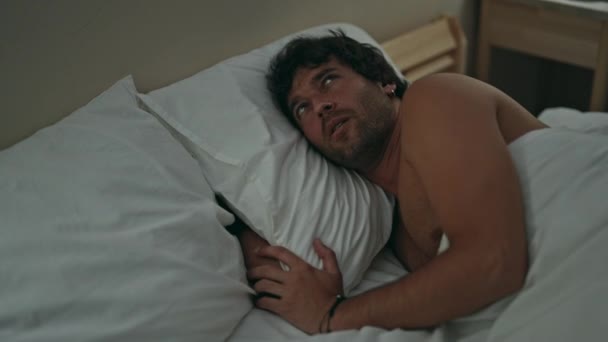 Fiatal spanyol férfi takarja fülét zaj feküdt az ágyon a hálószobában - Felvétel, videó