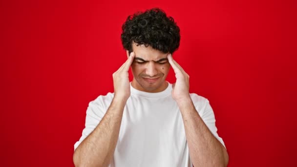 Mladý latinský muž trpí bolestí hlavy přes izolované červené pozadí - Záběry, video