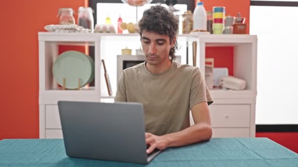 Jovem hispânico usando laptop sentado na mesa na sala de jantar - Filmagem, Vídeo
