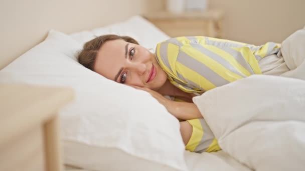 Jovem loira sorrindo confiante deitado na cama no quarto - Filmagem, Vídeo