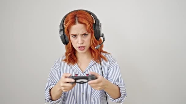 若い赤毛の女性は孤立した白い背景上のビデオゲームをする自信を持って微笑みます - 映像、動画