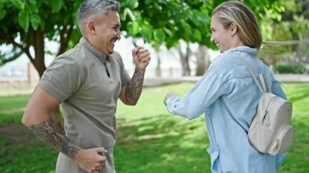 Uomo e donna coppia sorridente sicuro di sé ballare al parco - Filmati, video