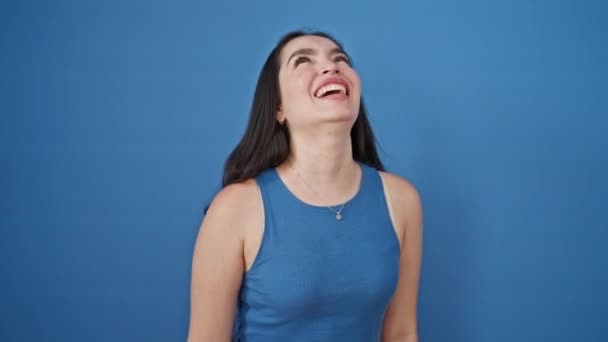 Νεαρή όμορφη ισπανόφωνη γυναίκα γελάει πολύ στέκεται πάνω από απομονωμένο μπλε φόντο - Πλάνα, βίντεο