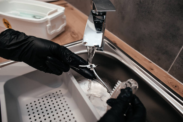 Maniküre-Werkzeuge unter fließendem Wasser waschen, Maniküre-Werkzeuge nach dem Eingriff desinfizieren, Maniküre-Werkzeuge in einer chemischen Lösung einweichen, - Foto, Bild