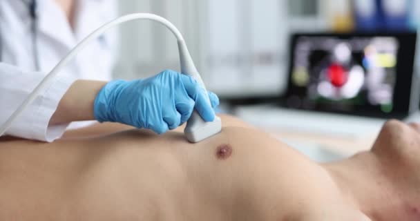 A cardiologist doctor makes an ultrasound of the heart to a man, close-up. Echocardiography, cardiovascular disease - Video, Çekim