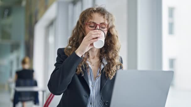 Jeune femme d'affaires utilisant un ordinateur portable souriant au bureau - Séquence, vidéo
