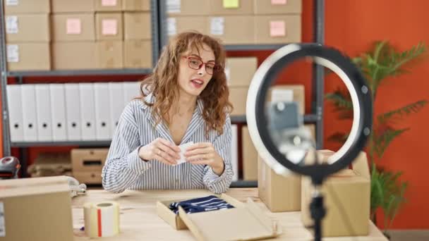 Jeune femme ecommerce travailleur d'affaires enregistrement tutoriel vidéo emballage vêtements sur boîte de carton au bureau - Séquence, vidéo
