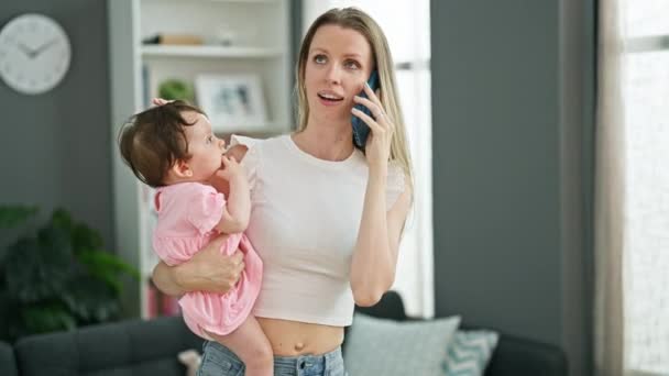 Madre e hija abrazándose entre sí hablando en el teléfono inteligente en casa - Metraje, vídeo
