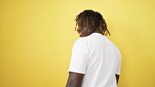 Afrikaanse amerikaanse man glimlachen zelfverzekerd staan over geïsoleerde gele achtergrond - Video