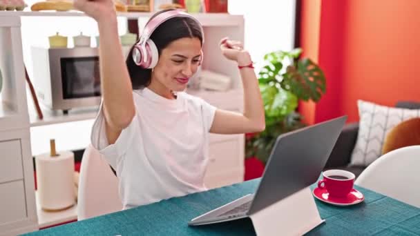 Νεαρή όμορφη ισπανόφωνη γυναίκα χαμογελά με αυτοπεποίθηση ακούγοντας μουσική και χορεύοντας στην τραπεζαρία - Πλάνα, βίντεο