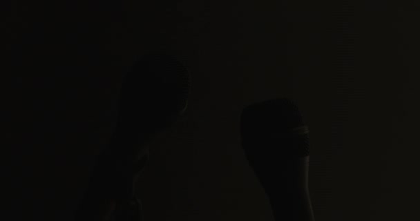 paire de microphones élégamment se lever et fondre dans l'obscurité gris-noir, mettant l'accent sur le concept de dialogue - Séquence, vidéo