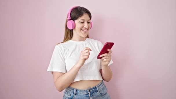 Giovane donna bionda che ascolta musica e danza su sfondo rosa isolato - Filmati, video