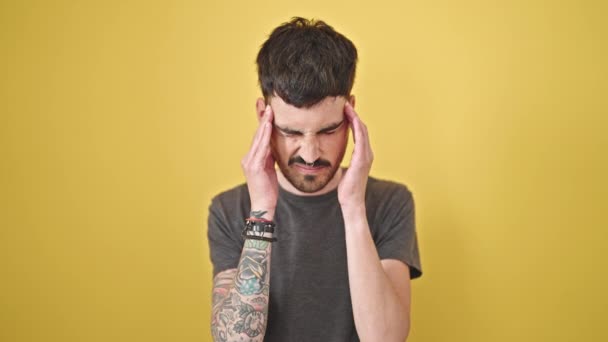 Hombre hispano joven que sufre de dolor de cabeza sobre un fondo amarillo aislado - Metraje, vídeo