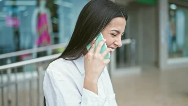 Genç, güzel İspanyol bir kadın akıllı telefondan konuşuyor. Sokakta gülümsüyor. - Video, Çekim