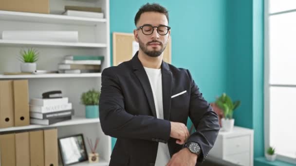 Νεαρός Άραβας επιχειρηματίας που στέκεται όρθιος με σταυρωμένα χέρια και σοβαρό πρόσωπο στο γραφείο - Πλάνα, βίντεο