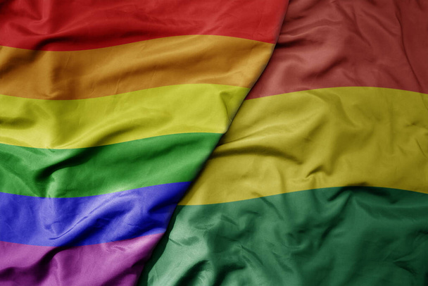 gran ondeando bandera colorida nacional realista de bolivia y bandera de orgullo gay arco iris. macro - Foto, imagen