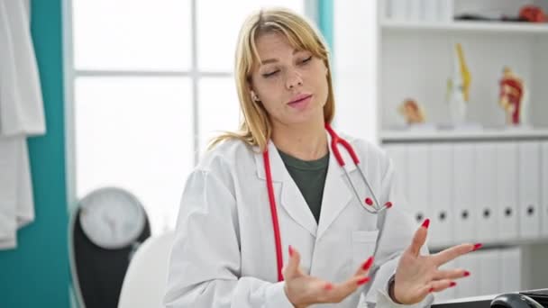 Νεαρή ξανθιά γυναίκα γιατρός μιλάει στην κλινική - Πλάνα, βίντεο