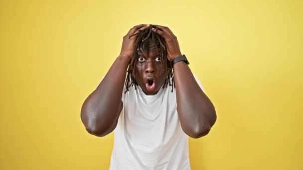 Afrikanischer Mann steht mit überraschendem Gesichtsausdruck vor isoliertem gelben Hintergrund - Filmmaterial, Video