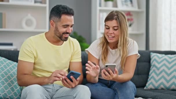 Kadın ve erkek, evdeki koltukta oturan akıllı telefonları kullanıyor. - Video, Çekim