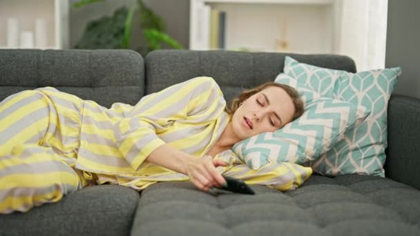 Mujer rubia joven tumbada en el sofá usando el teléfono inteligente durmiendo en casa - Metraje, vídeo