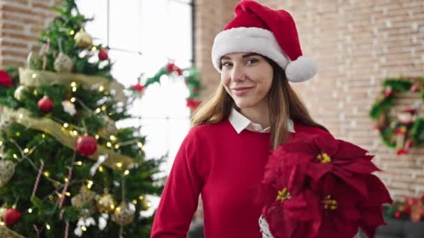 Mujer hispana joven sosteniendo planta de Navidad en casa - Imágenes, Vídeo