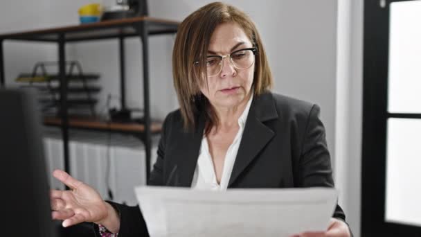 Mujer hispana de mediana edad trabajadora de negocios leyendo documento en la oficina - Imágenes, Vídeo