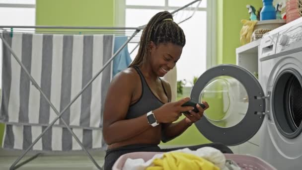 アフリカ系アメリカ人女性が洗濯室でビデオゲームをプレイ - 映像、動画
