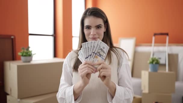 Junge schöne hispanische Frau lächelt zuversichtlich und hält Geld in ihrem neuen Zuhause - Filmmaterial, Video