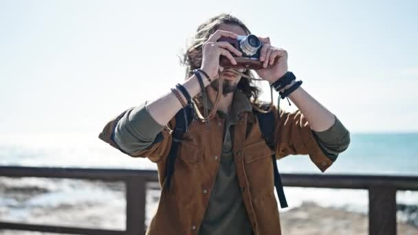Joven turista hispano usando mochila hacer foto en la playa - Metraje, vídeo