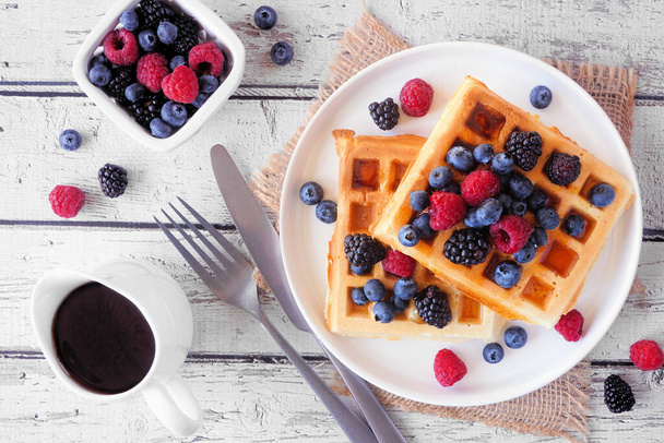 Breakfast waffles with raspberries and blueberries. Top down view table scene over a dark stone background. - Photo, Image