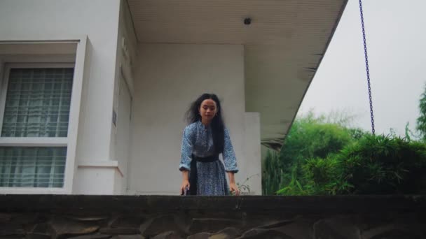 une femme asiatique marchant sur le mur du balcon en face de la maison heureusement le matin - Séquence, vidéo