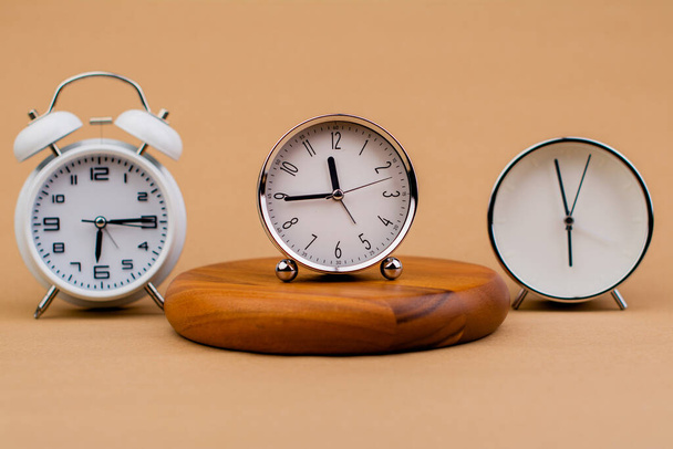 Wekker geplaatst op een houten statief, tijdwerkconcept de waarde van beperkte tijd Afspraken en stiptheid op het werk - Foto, afbeelding