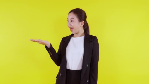 Portré fiatal ázsiai üzletasszony bemutató és bemutató döntés elszigetelt sárga háttér, reklám és marketing, nő meglepetés és izgatott, üzletasszony választás kifejezéssel. - Felvétel, videó