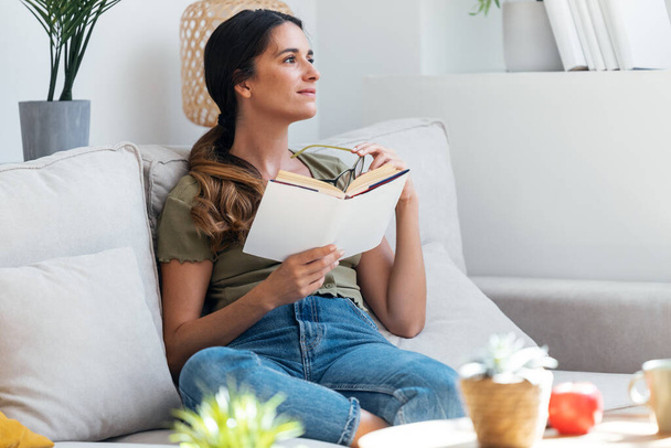 Shot of confident woman reading a book while sitting on sofa at home. - Foto, imagen