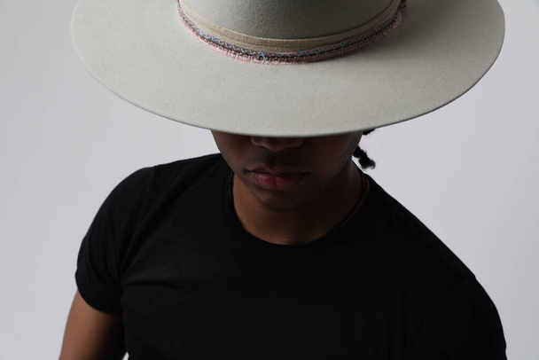 Handsome and carefree dark-skinned young man wearing trendy grey hat. Isolated. High quality photo.  - 写真・画像