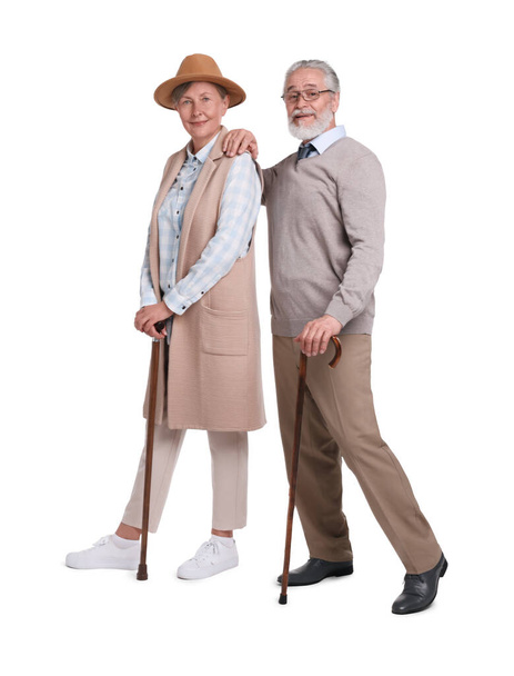Ανώτερος άνδρας και γυναίκα με μπαστούνια που περπατούν σε λευκό φόντο - Φωτογραφία, εικόνα