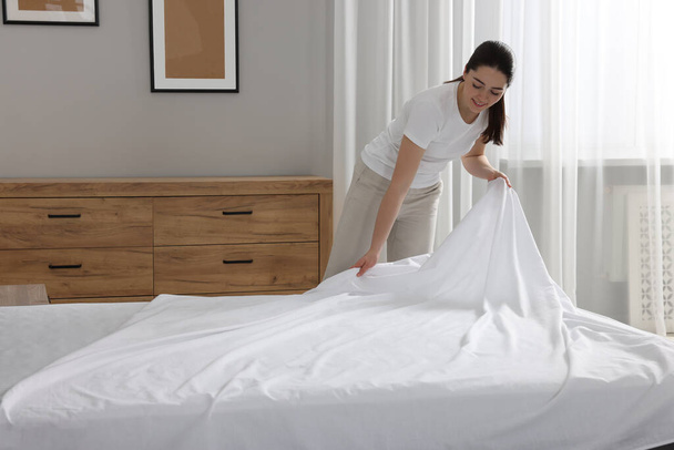 Young woman changing bed linens at home - Foto, immagini